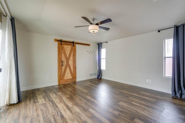 unfurnished room featuring dark hardwood / wood-style flooring, a barn door, and ceiling fan