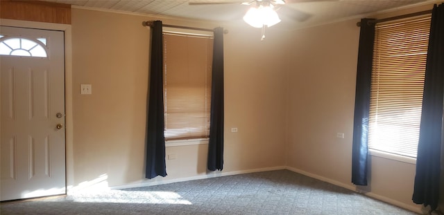 entryway featuring ceiling fan, light colored carpet, ornamental molding, and a healthy amount of sunlight