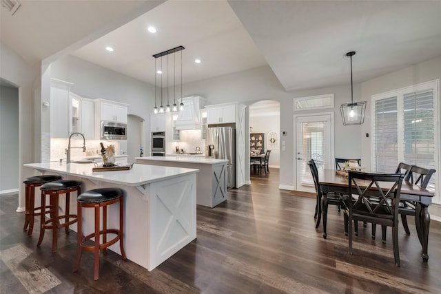 kitchen featuring pendant lighting, sink, stainless steel appliances, custom range hood, and white cabinets