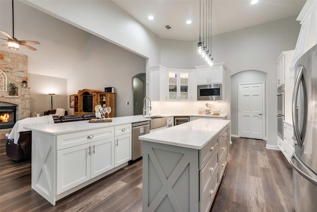 kitchen with stainless steel appliances, white cabinets, a fireplace, and kitchen peninsula