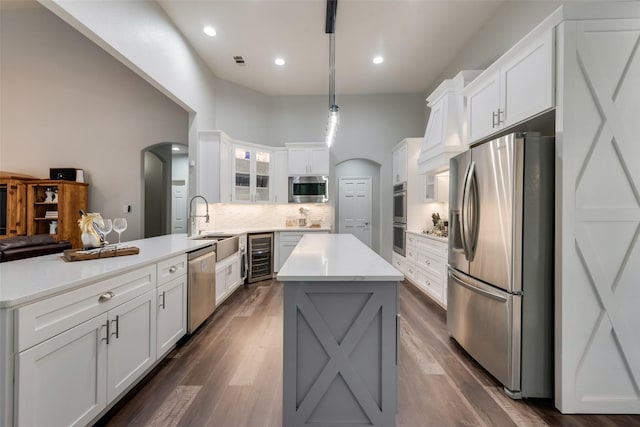 kitchen featuring stainless steel appliances, beverage cooler, kitchen peninsula, and white cabinets