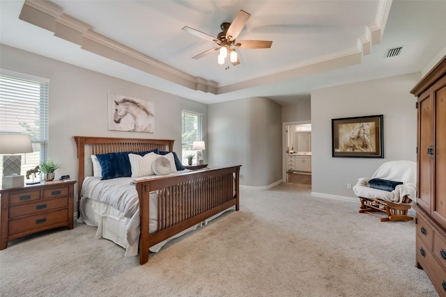 bedroom featuring a raised ceiling, ornamental molding, light carpet, and ensuite bath