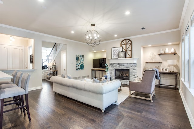 living room featuring dark hardwood / wood-style floors, ornamental molding, a fireplace, and a notable chandelier