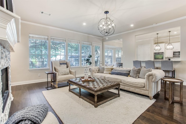 living room with dark hardwood / wood-style flooring, crown molding, a notable chandelier, and a fireplace