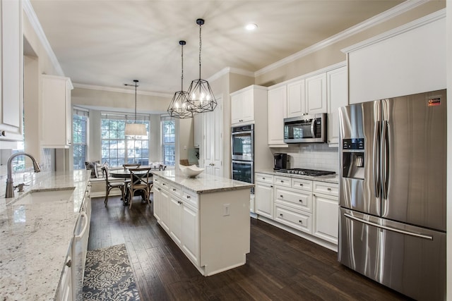 kitchen featuring a kitchen island, appliances with stainless steel finishes, sink, white cabinets, and hanging light fixtures