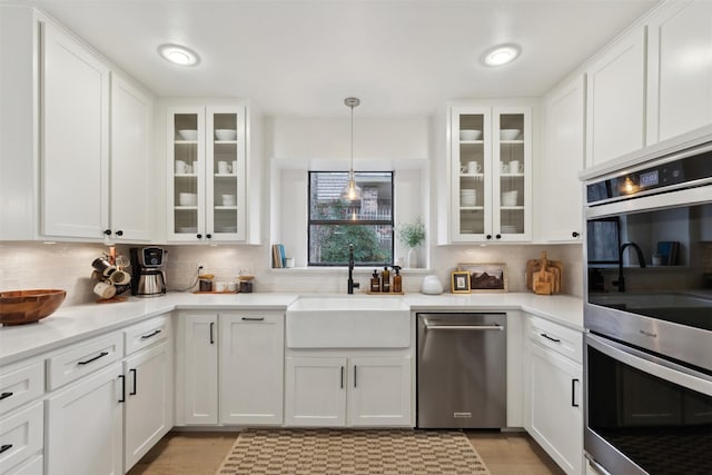 kitchen featuring stainless steel appliances, white cabinetry, sink, and pendant lighting