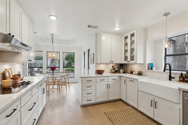 kitchen with black electric cooktop, sink, hanging light fixtures, and white cabinets