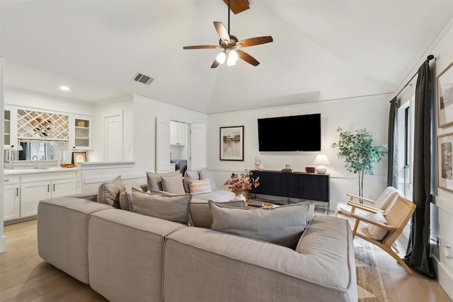 living room featuring ceiling fan, a healthy amount of sunlight, wet bar, and light hardwood / wood-style flooring