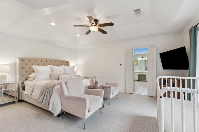 carpeted bedroom featuring ceiling fan, ensuite bathroom, and a tray ceiling