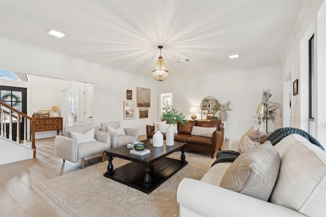 living room featuring crown molding, light wood-type flooring, and a notable chandelier