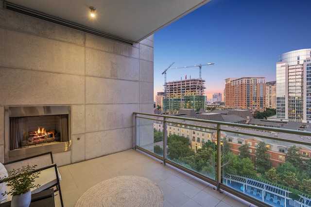 balcony at dusk featuring an outdoor fireplace