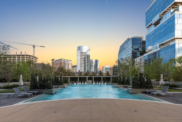 pool at dusk with pool water feature and a patio