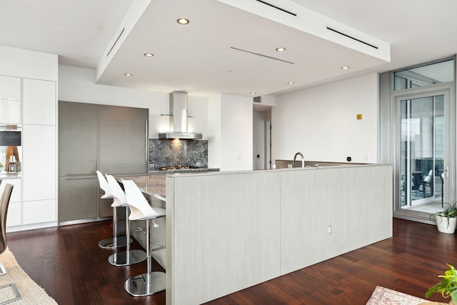 kitchen with extractor fan, white cabinets, backsplash, dark hardwood / wood-style flooring, and a large island