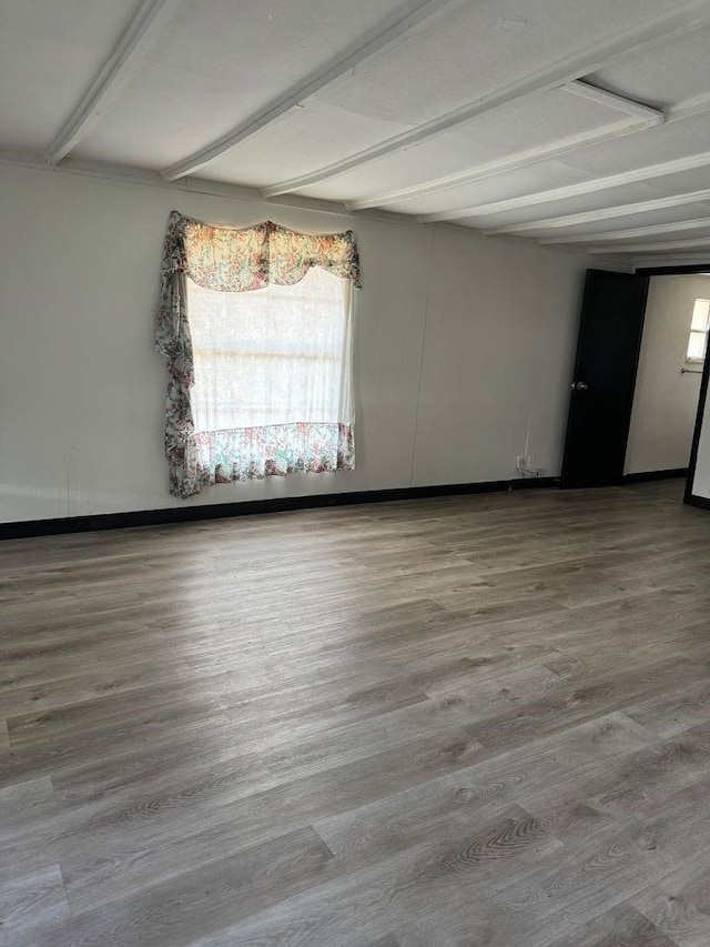 spare room with hardwood / wood-style flooring and beamed ceiling