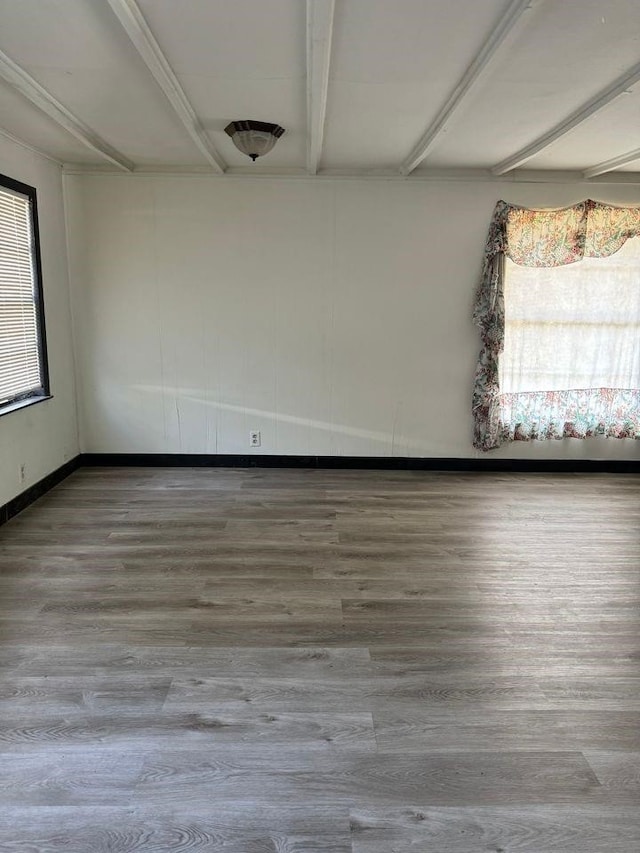 unfurnished room featuring wood-type flooring and beam ceiling