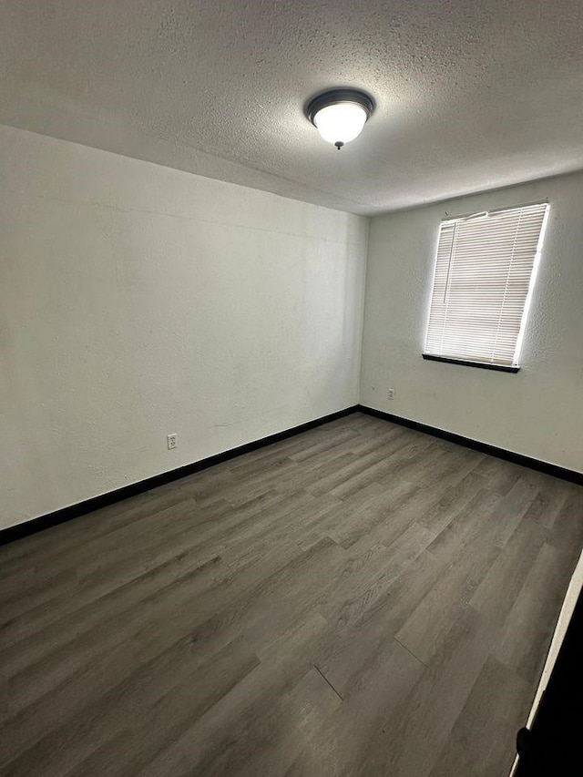 unfurnished room with wood-type flooring and a textured ceiling