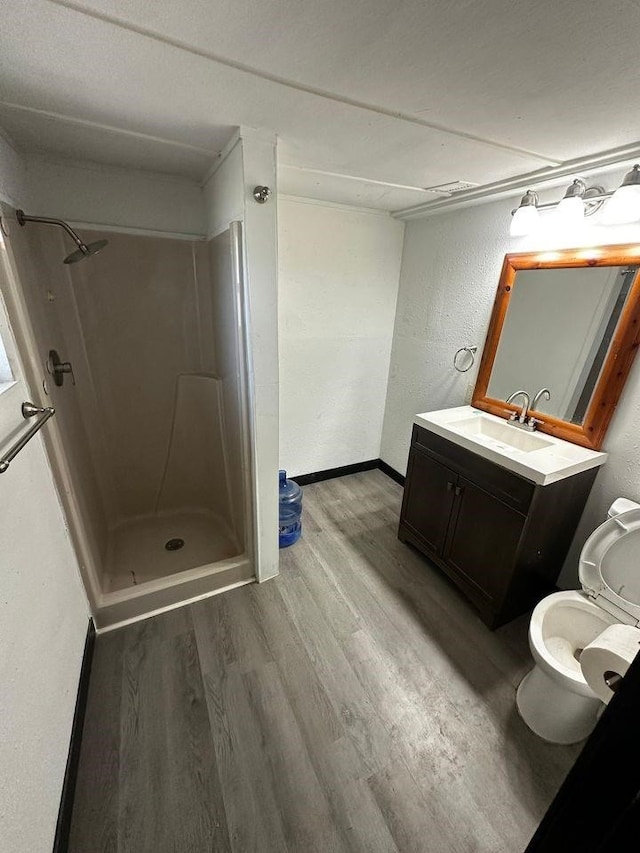 bathroom with vanity, hardwood / wood-style flooring, toilet, and a shower