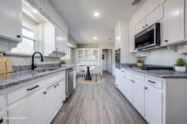 kitchen with a sink, stainless steel appliances, and white cabinetry