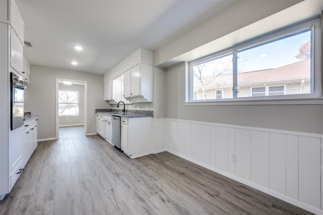 kitchen with stainless steel appliances, white cabinetry, and light hardwood / wood-style flooring