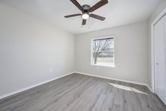 unfurnished bedroom featuring a ceiling fan, wood finished floors, baseboards, and a closet