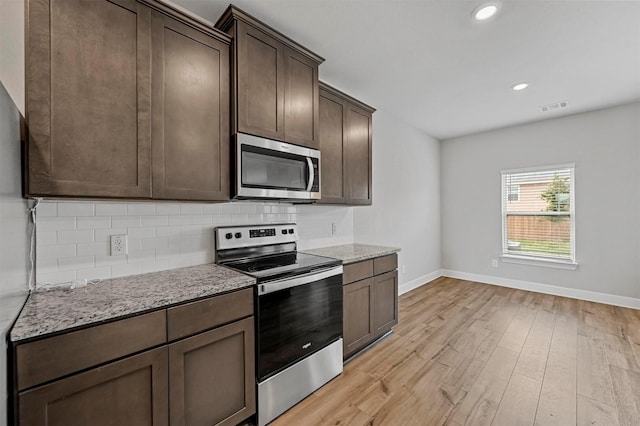 kitchen featuring tasteful backsplash, light stone counters, dark brown cabinetry, stainless steel appliances, and light hardwood / wood-style flooring