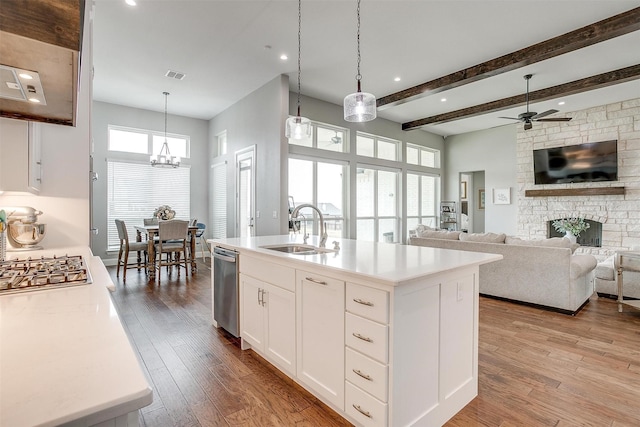 kitchen featuring pendant lighting, sink, light hardwood / wood-style floors, white cabinets, and a center island with sink