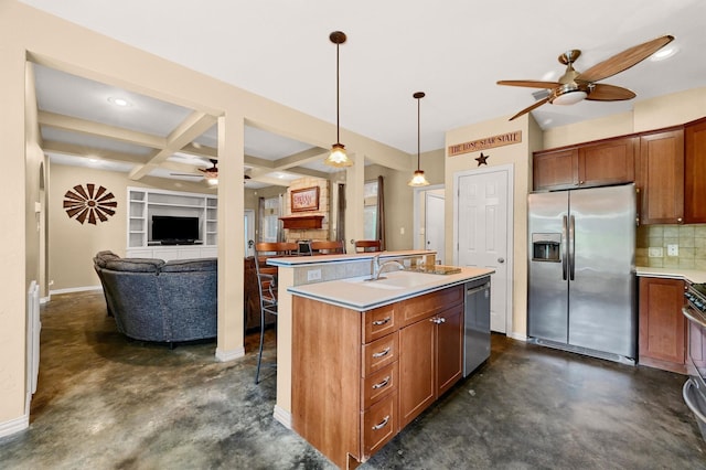 kitchen featuring pendant lighting, ceiling fan, appliances with stainless steel finishes, an island with sink, and decorative backsplash