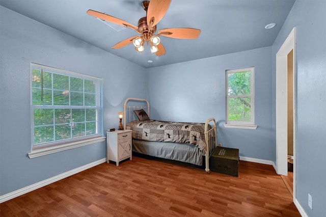 bedroom featuring multiple windows, wood-type flooring, and ceiling fan