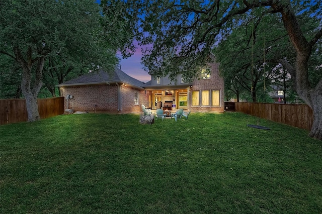 back house at dusk with a patio and a lawn