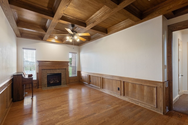 unfurnished living room featuring light wood-type flooring, wooden ceiling, beamed ceiling, ceiling fan, and a premium fireplace