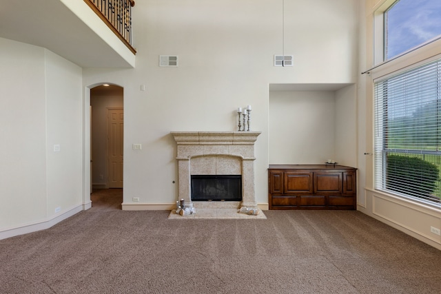 unfurnished living room with a towering ceiling and carpet flooring