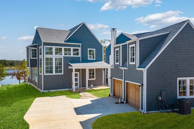 back of property with a garage, covered porch, a lawn, and central air condition unit