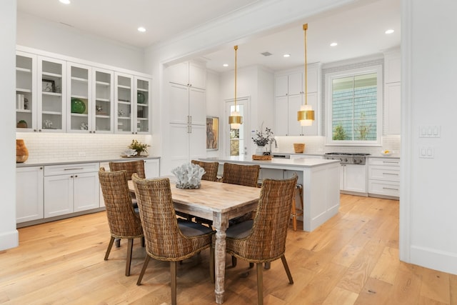 dining space with light hardwood / wood-style flooring and ornamental molding