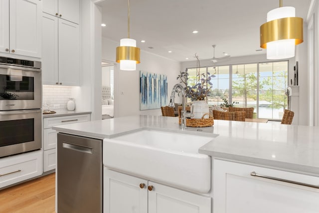 kitchen featuring appliances with stainless steel finishes, tasteful backsplash, sink, white cabinets, and hanging light fixtures