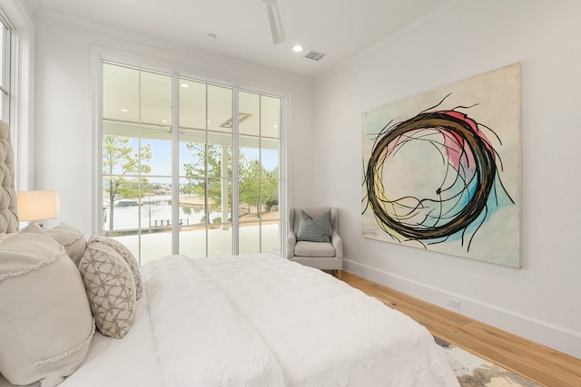 bedroom featuring hardwood / wood-style flooring, crown molding, a water view, and access to exterior