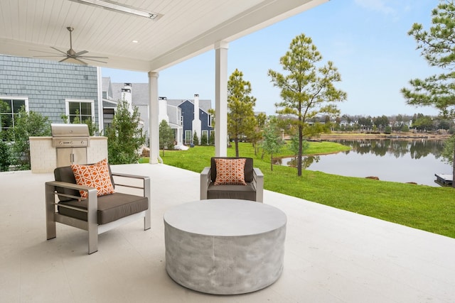 view of patio / terrace featuring a water view, ceiling fan, grilling area, and exterior kitchen