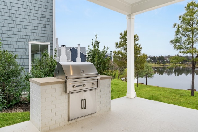 view of patio / terrace featuring a water view, an outdoor kitchen, and grilling area