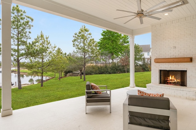 view of patio featuring a water view, ceiling fan, and an outdoor living space with a fireplace