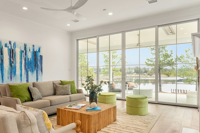 living room featuring ceiling fan, a water view, and light wood-type flooring