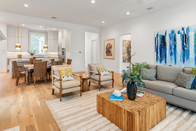 living room featuring crown molding and light hardwood / wood-style flooring