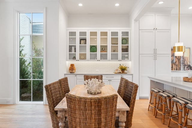 dining space featuring ornamental molding and light hardwood / wood-style flooring