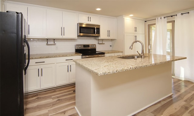 kitchen with appliances with stainless steel finishes, sink, a center island with sink, and white cabinets