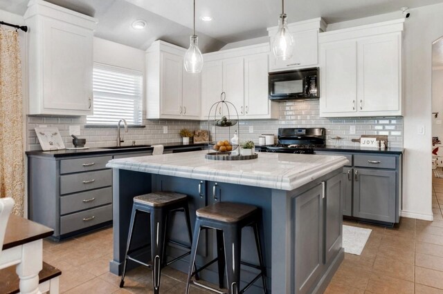 dining area featuring lofted ceiling, sink, and light tile patterned flooring