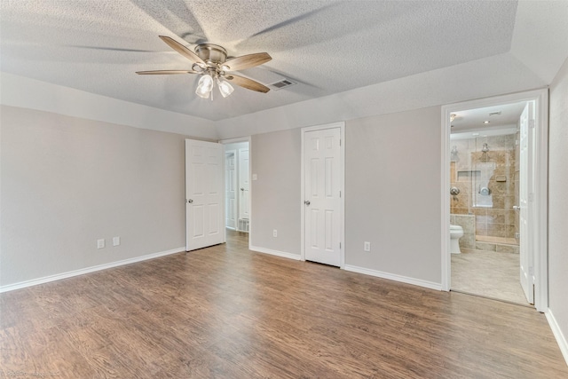 unfurnished bedroom with ensuite bath, wood-type flooring, and a textured ceiling