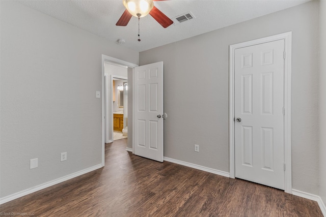 unfurnished bedroom with ceiling fan, dark hardwood / wood-style flooring, and a textured ceiling