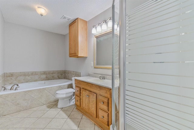 bathroom featuring tile patterned floors, toilet, a textured ceiling, vanity, and tiled bath