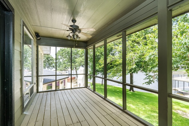 unfurnished sunroom featuring a water view, plenty of natural light, and ceiling fan