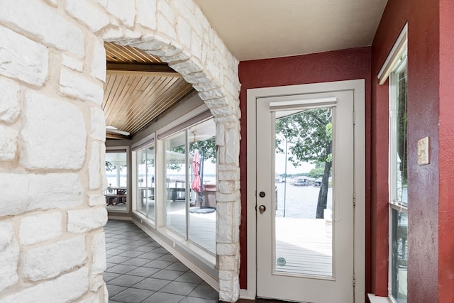 doorway featuring tile patterned flooring, a water view, and plenty of natural light