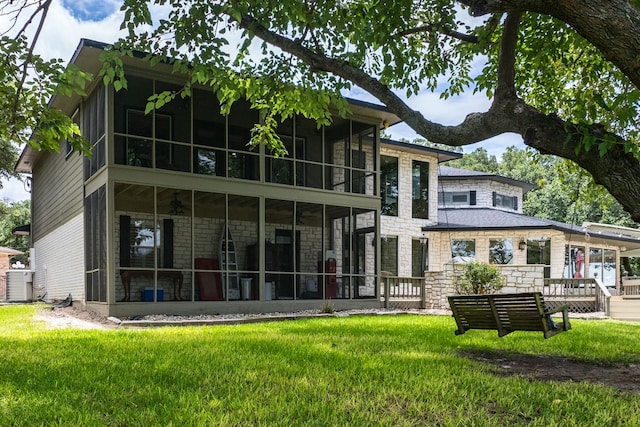 rear view of house featuring central AC unit, a yard, and a sunroom