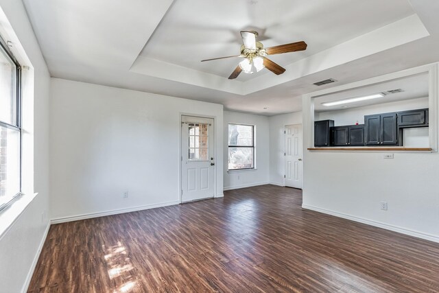 128 Black Forest Dr, Weatherford, TX 76086 - unfurnished living room featuring a tray ceiling, baseboards, ceiling fan, and dark wood-style flooring